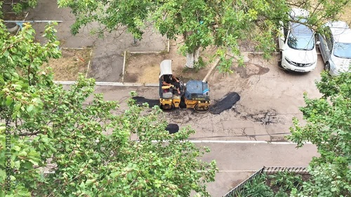  Road compacting equipment with worker from aerial view, construction maintenance of street asphalt, urban infrastructure work.