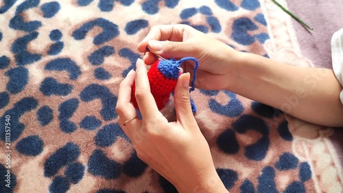 Person holding handmade knitted heart craft, hands holding red yarn heart with blue detail, handicraft hobby.