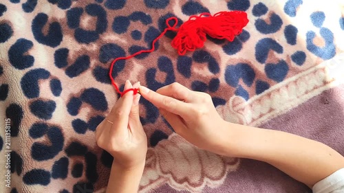 Person holding red yarn for knitting and crochet craft, hands working with fiber thread, handmade hobby.