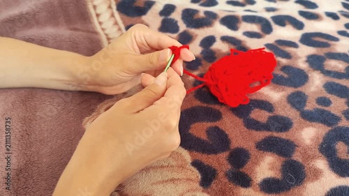  Person holding red yarn for knitting and crochet craft, hands working with fiber thread, handmade hobby.