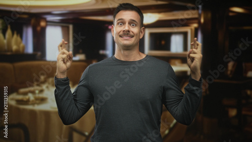 Bild auf Leinwand Man with moustache pressing hands together in prayer at a restaurant table inside a building; hopeful plea