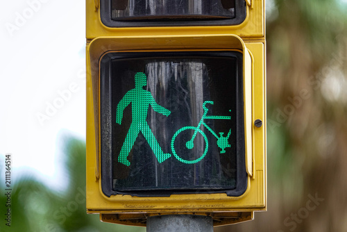 Green pedestrian and bicycle traffic signal at an urban intersection.