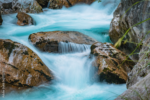 Konstfotografi Clear river water swiftly flowing through a narrow mountain gorge, surrounded by