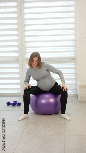 Expecting woman exercising on a fitness ball, staying active and healthy during her pregnancy journey