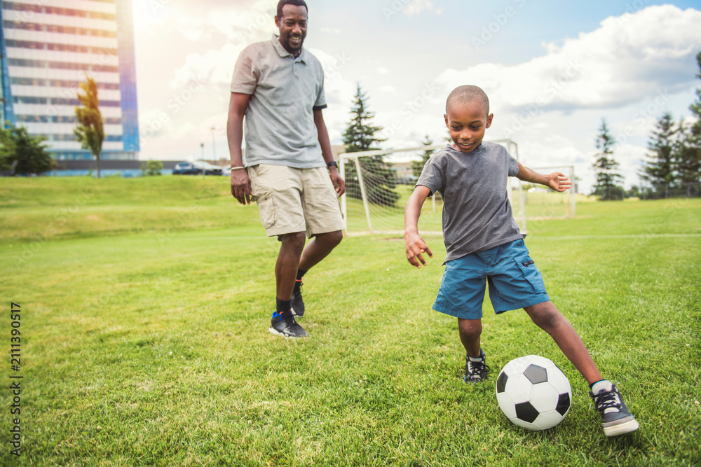 Obraz premium father with son playing football or soccer outside on field