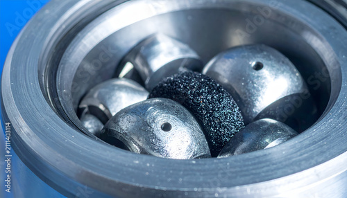 Close-up of Metal Bearings and a Porous Object in a Container.
