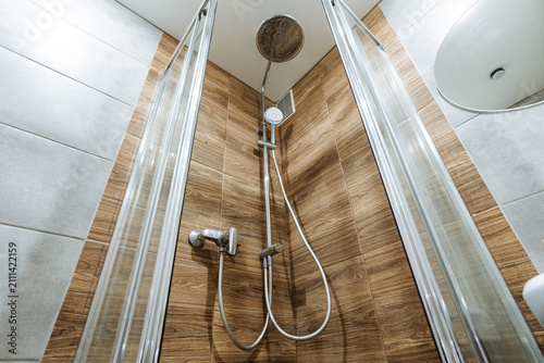 Quadro su tela Chrome showerhead and handheld unit in tiled bathroom corner with glass enclosur