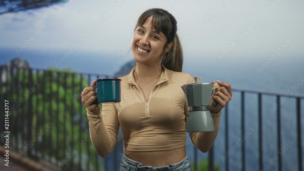 Obraz premium Woman holding teal mug and moka pot, smiling while offering cups on a balcony overlooking ocean and cliff; serenity morning ritual.