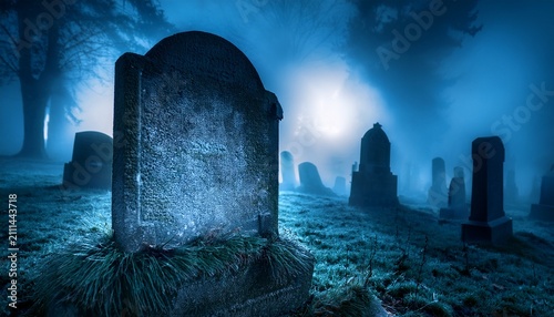 weathered gravestone in foggy cemetery at night