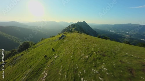 FPV Drone Flying Fast Over Lush Green Mountain Ridge Under Sunlight