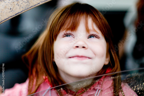 Canvas Print Close-up portrait of a smiling little girl looking up with curiosity, capturing childhood joy, innocence and genuine emotions