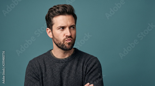 Confused Young Man with Beard Looking Sideways Expressing Doubt and Uncertainty