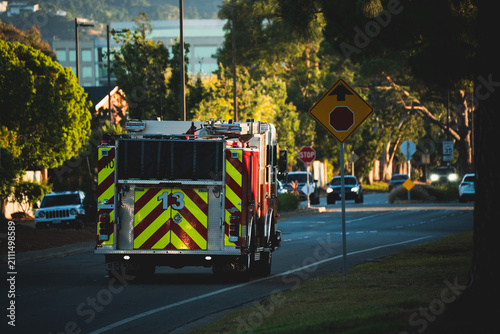 Fotografía Fire truck with reflective stripes drives down a suburban street