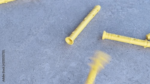Yellow dowels for installation and construction are scattered on a gray concrete background. Construction fasteners. Yellow expansion dowels for quick installation are spilled out on a gray surface