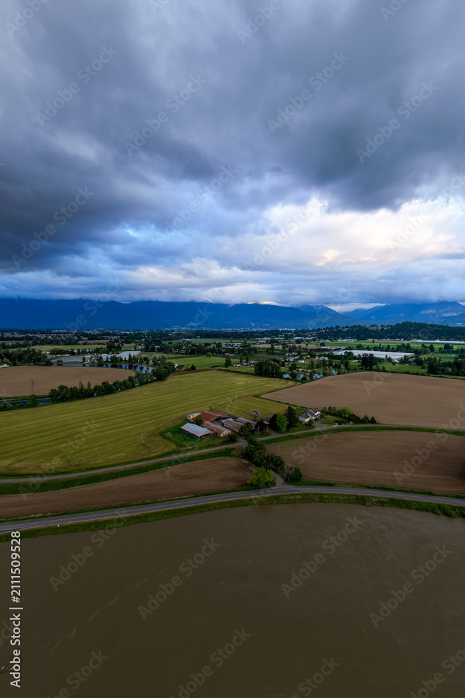Obraz premium Aerial View of Fraser Valley Farmland and River With Storm Clouds Over Chilliwack, British Columbia, Canada