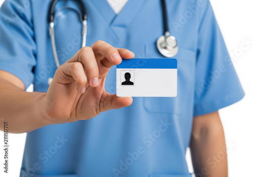 A Medical Professional In Blue Scrubs Holding A Blank Identification ID Card