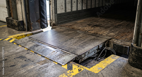 Close view of a dock leveler ramp and yellow safety markings at a warehouse loading dock entrance in an industrial logistics warehouse