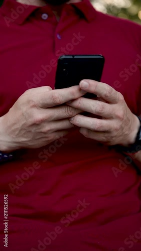 Close-up of hands typing on a phone. Close up view of hands holding modern smartphone, with thumbs actively typing message, browsing social media, or scrolling through news feed in a well lit indoor s