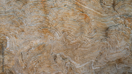 Fotografie Intricate wave pattern in folded sedimentary rock surface creating abstract natural texture