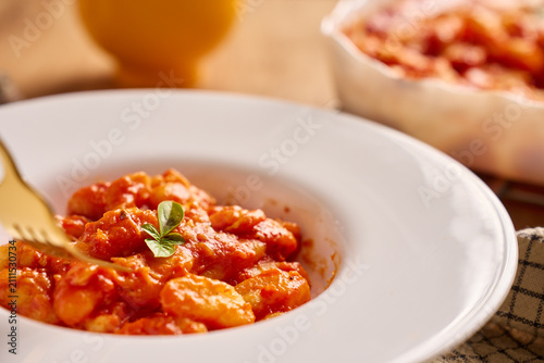 Gnocchi in tomato sauce served on plate with basil garnish and fork