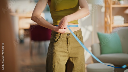 Photography Brunette measuring slim waist looking mirror after daily fitness routine closeup