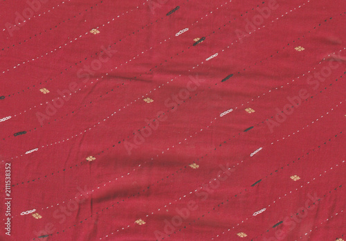 Red embroidered cotton fabric texture with white and gold thread diagonal stitches background