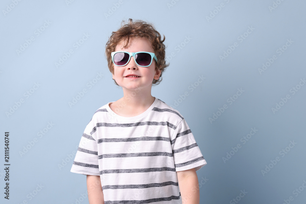 Fototapeta premium Smiling little boy in stylish sunglasses on grey background. Space for text