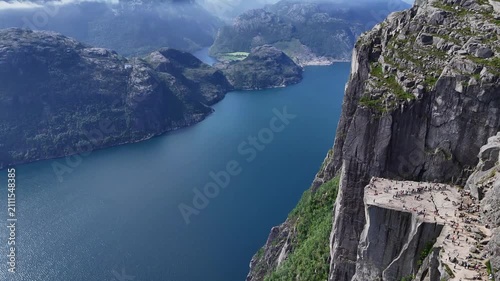 Drone panorama of steep cliff face and deep blue fjord waters near Preikestolen, Norway, on a clear summer day.