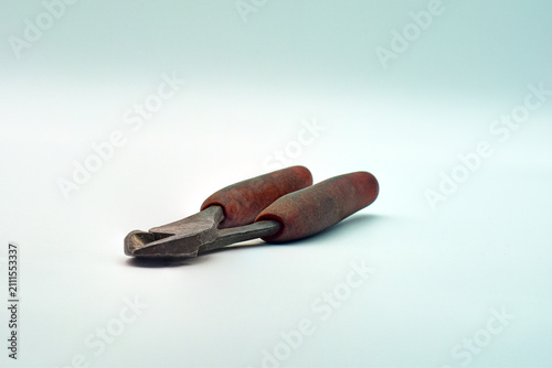 Rusty wire cutters with worn rubber handles on a clean surface, suggesting repair tools, vintage craftsmanship and everyday utility. Close-up studio shot highlights texture, wear and functional detail