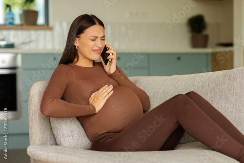 Bild auf Leinwand Expectant mother experiencing contractions and calling for support, holding her