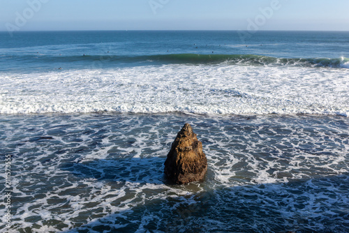 A lone rock formation stands amidst the crashing waves of the Pacific Ocean at Natural Bridges State Beach in Santa Cruz, California, USA.