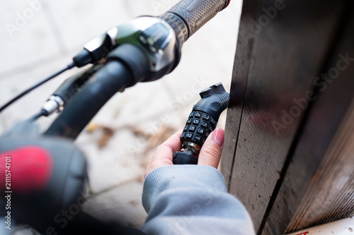 фотографія A close-up view shows a person unlocking a black combination cable lock on a bicycle