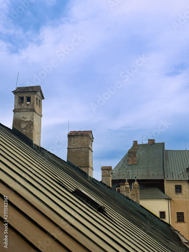 Fotografie Roofs and chimneys under a blue sky