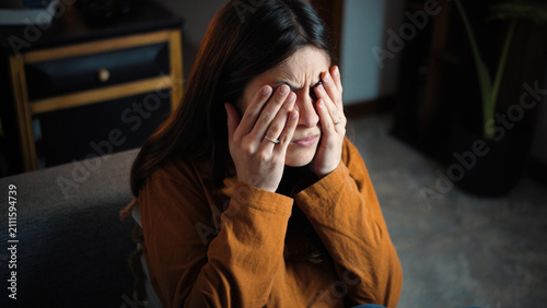 Fotografie Young Hispanic woman sitting on her sofa with itchy eyes and digital eye strain