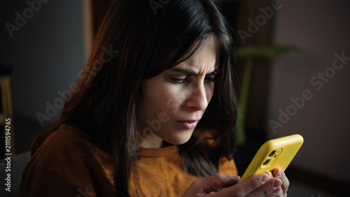 Foto Close-up of a young Caucasian woman straining her eyes to see her smartphone, re