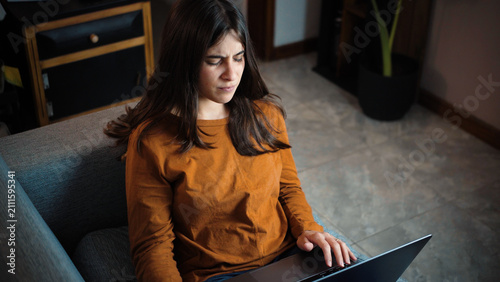Schilderij op canvas Young Latina woman straining her eyes to read her laptop screen, representing di