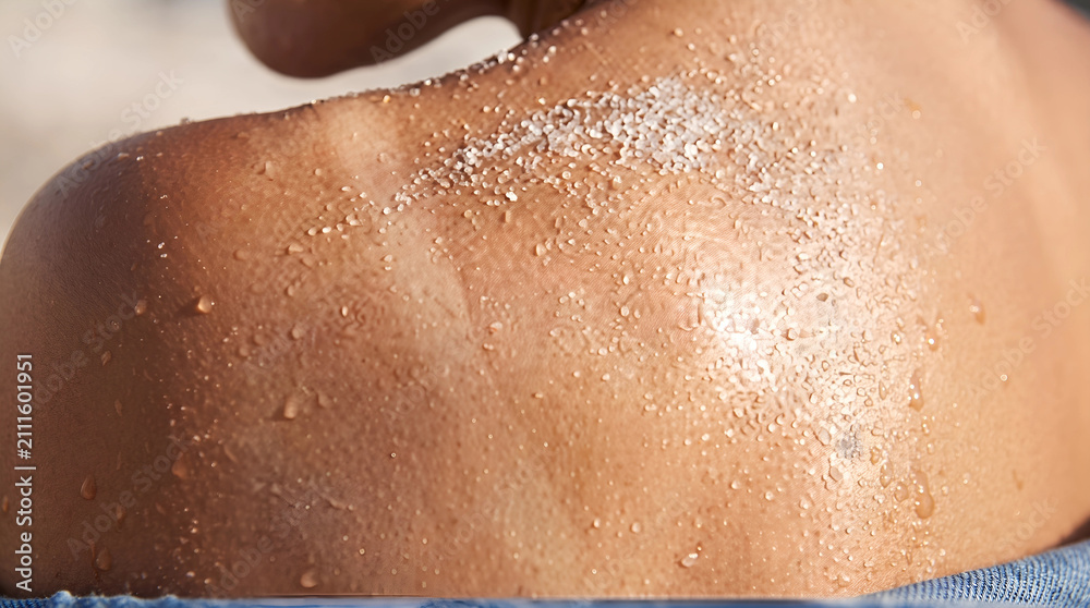 Fototapeta premium Macro view of sun-kissed human skin with sand and salt water residue, shoulder