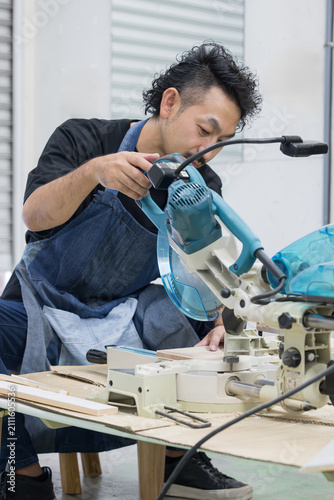 DIY・木工でスライド丸ノコを使って木材加工する男性職人 電動工具による趣味の家具製作の作業風景