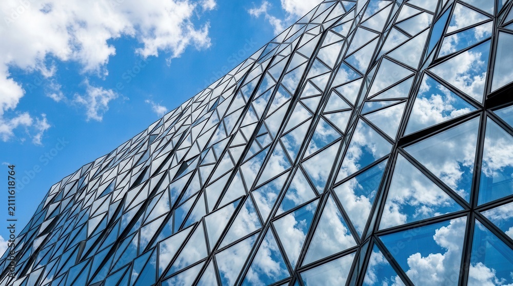 Fototapeta premium Modern Architectural Facade Reflecting Blue Sky and Clouds.