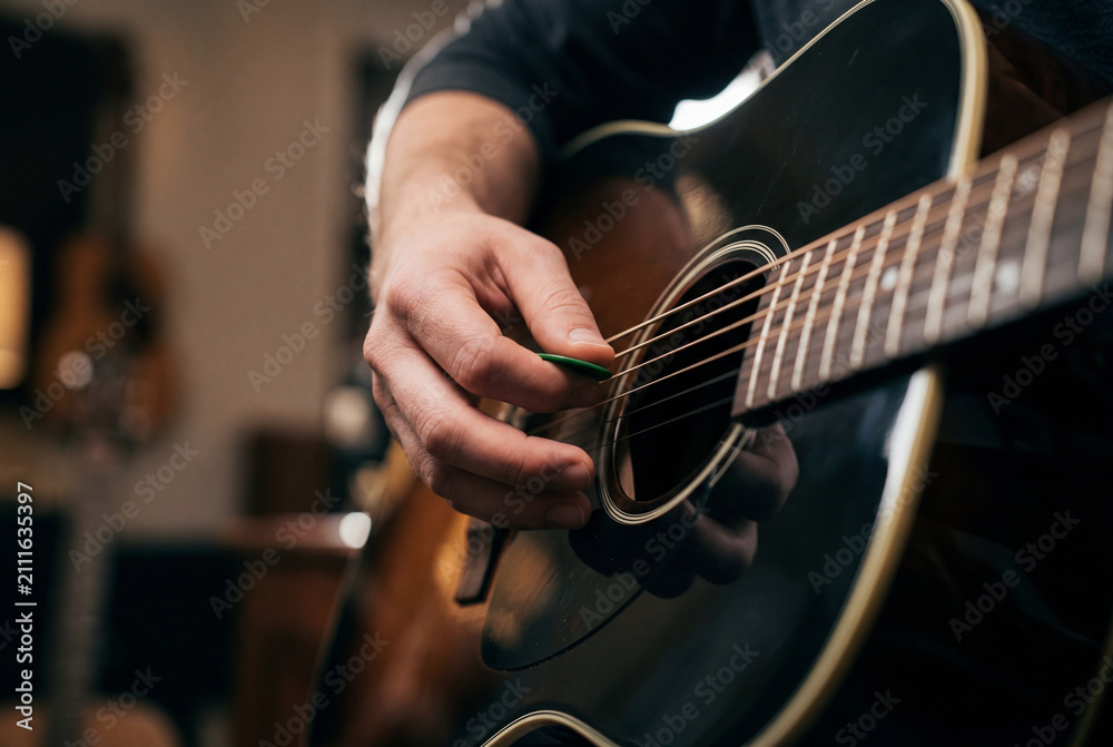Fototapeta premium Musician hand playing acoustic guitar with green pick