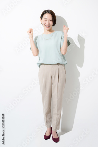 白背景で笑顔でガッツポーズをする日本人女性 成功・達成・応援を表現する働く女性の全身イメージ