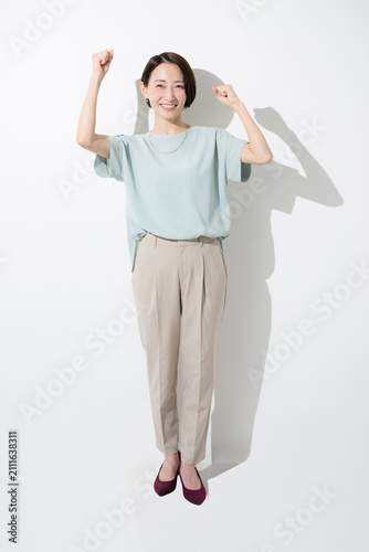 白背景で笑顔でガッツポーズをする日本人女性 成功・達成・応援を表現する働く女性の全身イメージ
