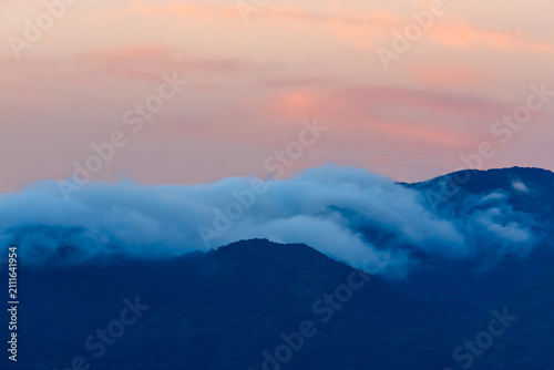 Bild auf Leinwand 茜に染まる薄明の空の下で山を越える滝雲20250721-1