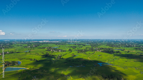 Konstfotografi An aerial panorama shows vast lush green farmland dotted with ponds and small settlements under a clear bright blue sky