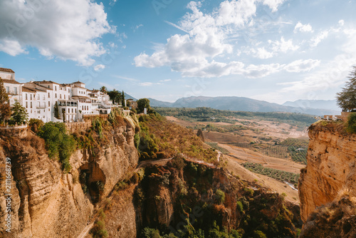 Ronda's traditional white buildings standing on a dramatic cliff edge, offering expansive views of El Tajo gorge and the surrounding picturesque Andalusian landscape in Malaga, Spain