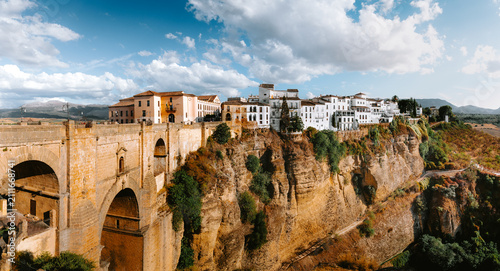 Iconic Puente Nuevo bridge connecting the historic old town buildings with the new town across El Tajo gorge in Ronda, Malaga, Andalucia, Spain, under a blue sky with clouds