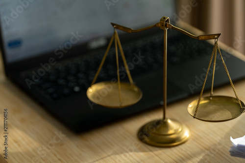 Bild auf Leinwand Golden scales rest beside a laptop on wooden surface