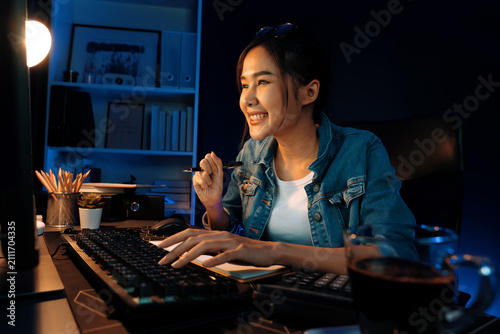Canvastavla Smiling young beautiful asian creative officer looking on pc in sales target online, earning job's freelancer for planning invest new strategy marketing online planning at neon light night