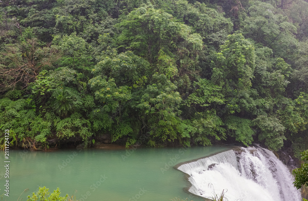 Fototapeta premium Majestic Shifen Waterfall in Pingxi District, New Taipei City. A popular natural tourist attraction in Taiwan featuring powerful cascading water and lush green foliage.