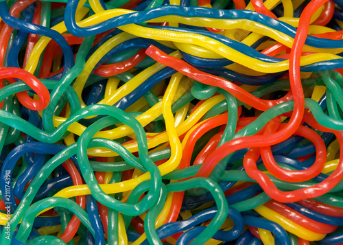 Close up of colorful strings of licorice in multiple flavors. Yellow, green, blue and red tangled up together in a pile.